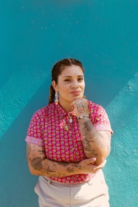 a woman with tattoos leaning against a blue wall