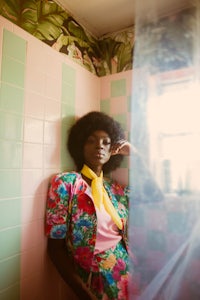 a woman with an afro sitting in a pink bathroom