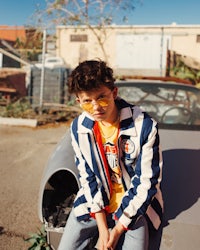 a young man sitting on top of a car