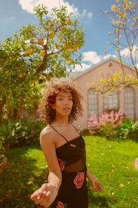 a young woman in a black dress standing in front of an orange tree